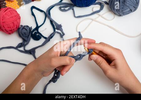 Différentes billes de fils de couleur. Les mains des enfants sont crochetées et la vue sur les filets de mousse ci-dessus sur la table blanche Banque D'Images