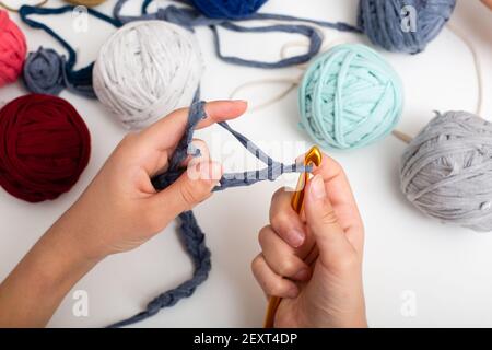 Différentes billes de fils de couleur. Les mains des enfants sont crochetées et la vue sur les filets de mousse ci-dessus sur la table blanche Banque D'Images