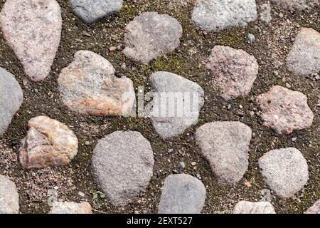 Ancienne chaussée avec pierres rondes en granit dans le sol, vue de dessus, texture de photo d'arrière-plan Banque D'Images