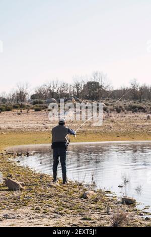 Un homme jette sa canne à pêche pour attraper du poisson un lac l'après-midi d'été Banque D'Images