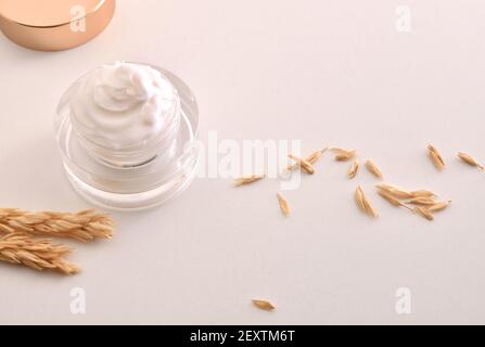 Crème hydratante pour le corps et le visage d'avoine dans un pot en verre avec des pointes sur une table en bois avec fond blanc isolé. Vue en hauteur. Banque D'Images