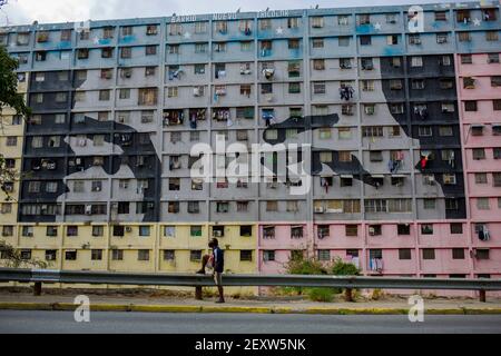 Caracas, Venezuela. 04e mars 2021. Un homme se tient devant un bâtiment avec une murale montrant les yeux du président vénézuélien Hugo Chavez. Le Venezuela a développé un culte de la personnalité autour de feu président et il est commun de trouver des peintures murales avec son visage dans la capitale. Le vendredi 5 mars marque le huitième anniversaire de sa mort. Credit: Pedro Ramses Mattey/dpa/Alay Live News Banque D'Images