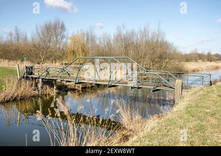 Puttershoek, pays-Bas, 26 février 2021 : ancien pont piétonnier en acier traversant un étroit canal dans la polder Banque D'Images