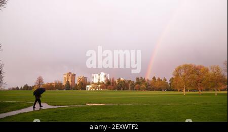 Arc-en-ciel apparaît au-dessus du parc pendant le parapluie piéton Thunderstorm Banque D'Images