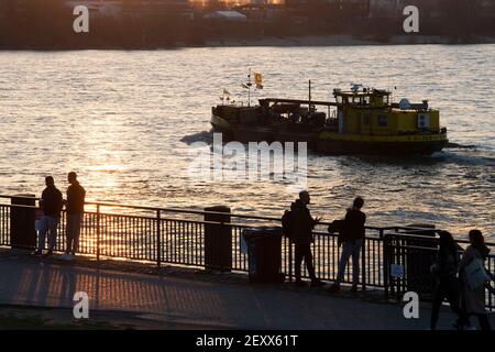 Düsseldorf, Allemagne. 02 mars 2021. Les gens se tiennent sur les rives du Rhin à Düsseldorf et regardent un navire dans le Rhin, humeur du soir, panorama, vue d'ensemble, général, caractéristique, motif bord, 02.03.2021. Â | utilisation dans le monde crédit: dpa/Alay Live News Banque D'Images