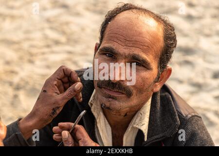 un barber coupant les cheveux de pèlerin pendant la mela kumbh dans aridawar.kumbh est la plus grande congrégation sur la terre. Banque D'Images