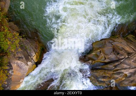 Vue aérienne de la cascade de la rivière avec de l'eau turquoise claire tombant entre des blocs mouillés avec de la mousse blanche épaisse. Banque D'Images