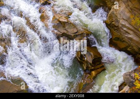 Vue aérienne de la cascade de la rivière avec de l'eau turquoise claire tombant entre des blocs mouillés avec de la mousse blanche épaisse. Banque D'Images