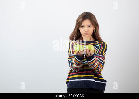 Jeune femme vêtue de vêtements décontractés avec des pommes vertes arrière-plan blanc Banque D'Images