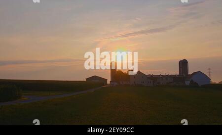 Vue sur un lever de soleil avec vue sur une ferme Amish Ferme de Barn et Silos Banque D'Images