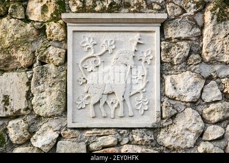 Bakhchisarai, Crimée - 25 janvier 2021 : dalle avec un ancien relief sculpté représentant un agneau de dieu, enchâssée dans une clôture en pierre Banque D'Images