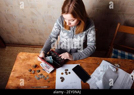 la baisse des revenus et la crise financière, les dépenses élevées en matière d'appartement et de services publics, les filles fatiguées remplissent les déclarations de revenus Banque D'Images