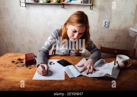 la baisse des revenus et la crise financière, les dépenses élevées en matière d'appartement et de services publics, les filles fatiguées remplissent les déclarations de revenus Banque D'Images