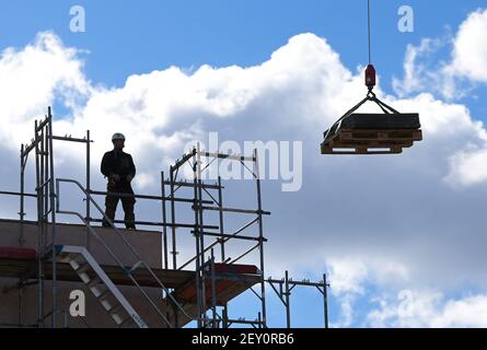 05 mars 2021, Brandebourg, Potsdam : un ouvrier dirige une grue sur le chantier de construction Georg-Hermann-Allee. Lors d'un événement de presse sur ce qui est actuellement le plus grand nouveau projet de construction de l'association de logement municipal ProPotsdam, une campagne d'information a été présentée. L'administration de la ville et ProPotsdam veulent sensibiliser les gens au certificat d'admissibilité au logement WBSplus, qui s'adresse aux ménages à revenu faible ou moyen. La plupart des 274 appartements de Bornstedter Feld sont subventionnés publiquement, ce qui permet des loyers socialement acceptables. Photo: Soeren Stache/dpa-Zentral Banque D'Images