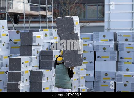 05 mars 2021, Brandebourg, Potsdam: Un ouvrier transporte des colis isolants sur le chantier de Georg-Hermann-Allee. Lors d'un événement de presse sur ce qui est actuellement le plus grand nouveau projet de construction de l'association de logement municipal ProPotsdam, une campagne d'information a été présentée. La municipalité et ProPotsdam veulent faire mieux connaître l'offre du certificat d'admissibilité au logement WBSplus, qui s'adresse aux ménages à revenu faible ou moyen. La plupart des 274 appartements de Bornstedter Feld sont subventionnés publiquement, ce qui permet des loyers socialement acceptables. Photo: Soeren S. Banque D'Images