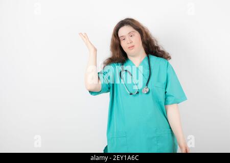 Jeune femme médecin avec le syndrome de Down debout sur fond blanc Banque D'Images