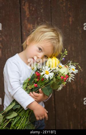 Garçon blond, bouquet de fleurs hodgling, portrait rapproché Banque D'Images