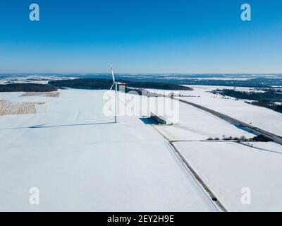 Vue aérienne de l'éolienne dans un paysage couvert de neige à côté À l'autoroute A8 près d'Ulm dans le sud de l'Allemagne sur a jour d'hiver ensoleillé avec grand ciel bleu et Banque D'Images