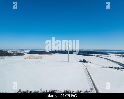 Vue aérienne de l'éolienne dans un paysage couvert de neige à côté À l'autoroute A8 près d'Ulm dans le sud de l'Allemagne sur a jour d'hiver ensoleillé avec grand ciel bleu et Banque D'Images