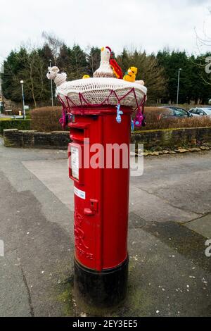 Housse tricotée pour animaux sur une boîte postale rouge.Angleterre, Royaume-Uni. Banque D'Images