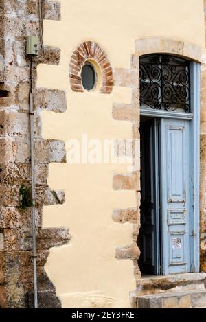 Porte bleue, fenêtre ronde en brique et détails en pierre à Chania, Crète, Grèce. Banque D'Images