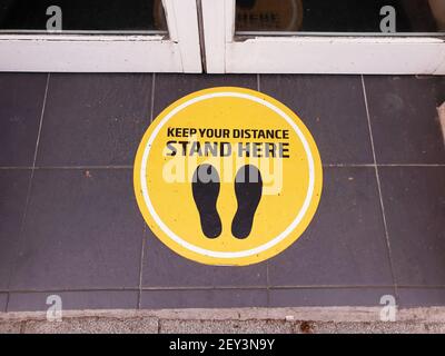 BRAY, IRLANDE - 22 avril 2020 : signe de distance sociale sur le sol avec le message « Keep Your distance Stand here ». Le panneau à l'entrée de local Banque D'Images