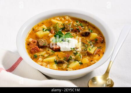 Rassolnik, bœuf, orge, carotte et soupe au cornichon. Cuit à base de concombre salé-aigre. Servi dans un bol blanc sur une nappe en tissu blanc. Style avec Banque D'Images