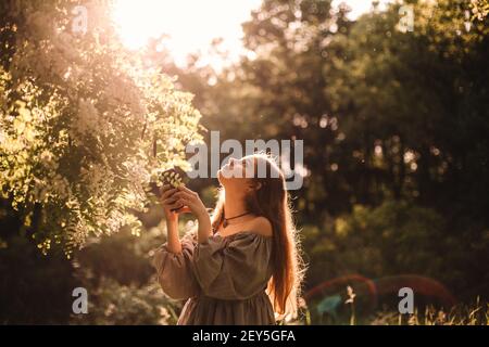 Une adolescente cherche en se tenant debout près de l'arbre en fleurs stationnement Banque D'Images