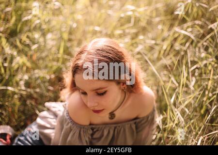 Portrait d'une adolescente assise sur le terrain dans l'herbe en été Banque D'Images