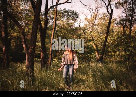 Une adolescente qui marche à travers l'herbe verte dans la forêt pendant l'été Banque D'Images