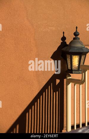 lampe extérieure ou lanterne contre blanc orange pêche couleur maison extérieure ciment mur texturé avec ombre de la rampe d'escalier dans le coin inférieur Banque D'Images