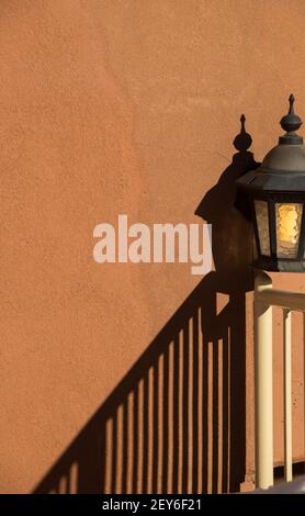 lampe extérieure ou lanterne contre blanc orange pêche couleur maison extérieure ciment mur texturé avec ombre de la rampe d'escalier dans le coin inférieur Banque D'Images