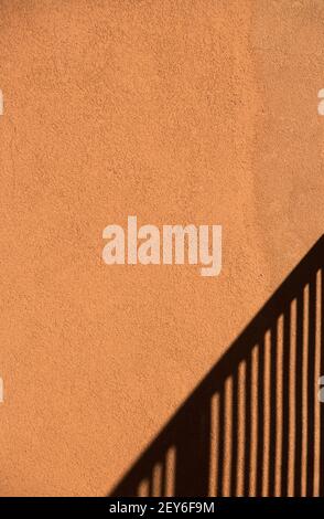 ombre de la main courante d'escalier sur orange pêche extérieur ciment mur de la maison lignes noires de la poignée d'escalier ombre format vertical salle pour le type Banque D'Images