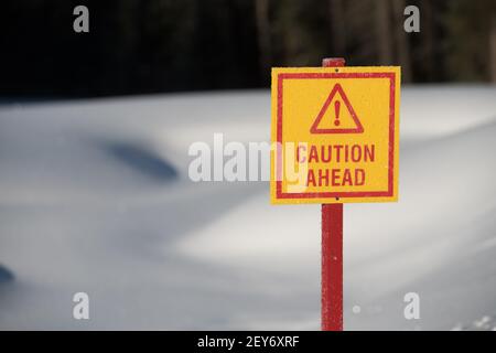 attention, signe triangle avec point d'exclamation dans la neige jaune et rouge en arrière-plan avertissant de la glace mince devant l'étang sur le terrain de golf en hiver Banque D'Images