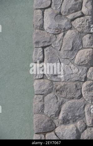 partie de la cheminée extérieure en pierre sur le mur extérieur en béton de la maison gros plan pierres placées au hasard par maçon de forme irrégulière roches comme espace vide face Banque D'Images