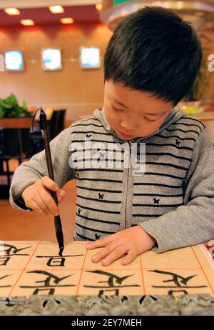 SUZHOU, CHINE-NOVEMBRE 26, 2008: Le garçon chinois apprend à écrire des caractères chinois, la calligraphie est la culture traditionnelle de la chine Banque D'Images