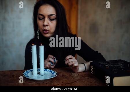 une fille de fortune teller allume des bougies pour prédire l'avenir. rituel mystique de la communication avec les esprits Banque D'Images