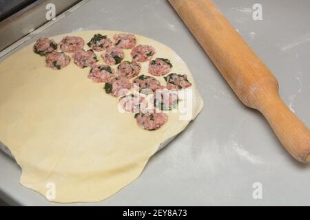 Processus de fabrication de boulettes maison sous forme spéciale. Pâte de farine blanche et viande hachée aux épinards. Cuisine. Banque D'Images