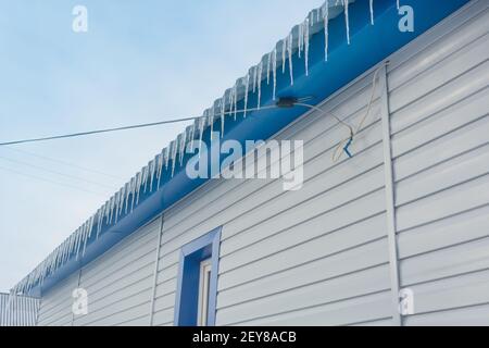 Glaces nettes et transparentes sur le toit de la maison en hiver. Gros plan, mise au point sélective. Banque D'Images