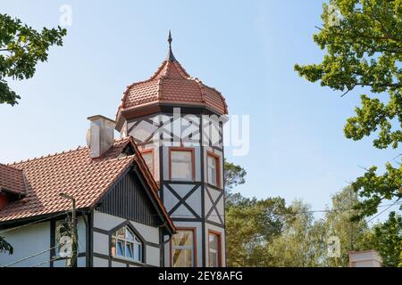 Le bâtiment est une tour avec des fenêtres et une décoration à colombages. Toit en carreaux rouges en forme de dôme avec flèche. Architecture allemande. Gros plan, sélectif Banque D'Images