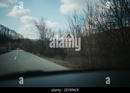 Un point de mire sélectif d'un virage serré devant le panneau de signalisation le côté d'une route dans une campagne Banque D'Images