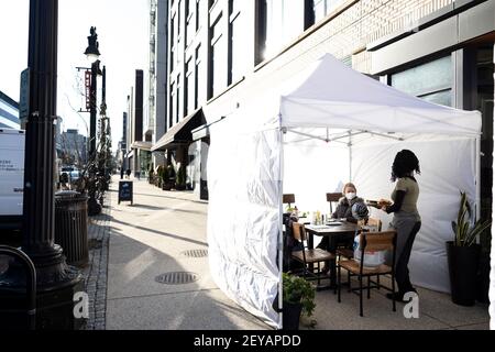 Washington, États-Unis. 5 mars 2021. Les gens s'assoient dans une tente de restaurant à Washington, DC, aux États-Unis, le 5 mars 2021. Les employeurs américains ont ajouté 379,000 emplois en février, le taux de chômage ayant peu changé à 6.2 p. 100, a indiqué vendredi le ministère du travail. En février, la plupart des gains d'emploi se sont produits dans les loisirs et l'accueil, avec des gains plus faibles dans les services d'aide temporaire, les soins de santé et l'aide sociale, le commerce de détail et la fabrication, selon le rapport mensuel publié par le Bureau de la statistique du travail du Ministère. Credit: Ting Shen/Xinhua/Alay Live News Banque D'Images