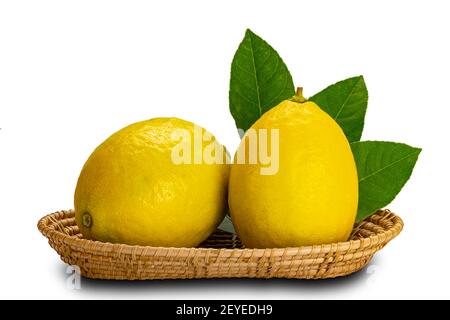 Citrons avec feuilles dans un plateau en bambou sur fond blanc avec masque. Banque D'Images