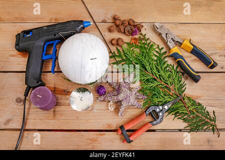 Fleuriste au travail: Femme montre comment faire boule de Noël avec sphère de styromousse et brindilles de thuja. Étape par étape, tutoriel. Banque D'Images