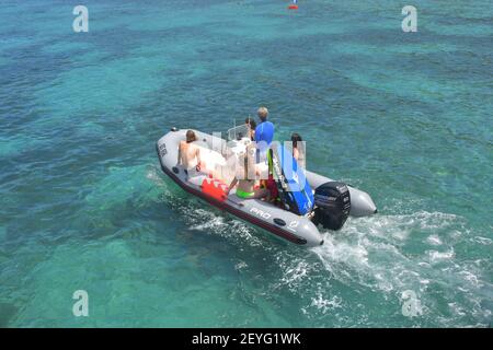 Famille roulant lentement dans LA CÔTE avec console centrale et moderne moteur hors-bord sur des eaux claires et peu profondes avec formations de récifs et des zones sablonneuses sur le bott Banque D'Images
