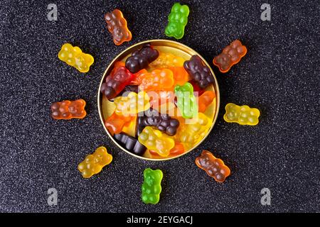 Des ours délicieux disposés en forme de soleil autour d'une boîte de bonbons sur un fond enrobé de sucre. Banque D'Images