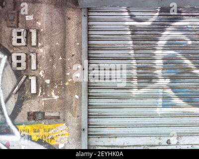 Mur de la ville avec numéro de maison et graffiti et porte en métal enroule vers le haut à Bangkok, Thaïlande. Banque D'Images