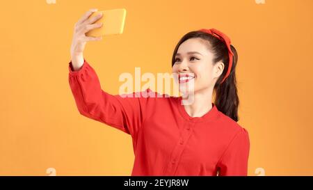 Smiling young girl making photo selfies sur smartphone Blackberry sur fond jaune Banque D'Images