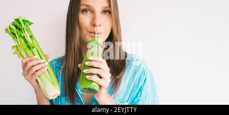 La femme tient un bouquet de branche de céleri frais et des boissons fraîches jus de céleri maison Banque D'Images