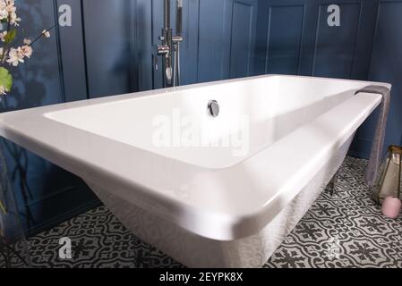 Une baignoire dans une salle de bains avec des murs bleu foncé et carrelage en céramique à motifs Banque D'Images